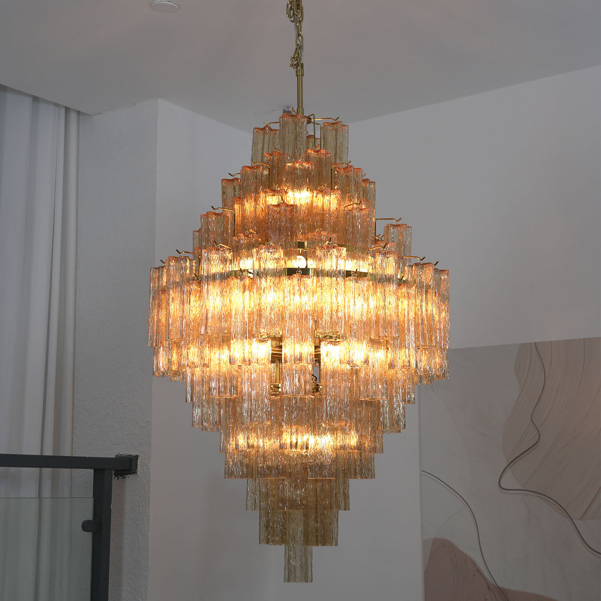 Addis Diamond Chandelier with glowing amber glass in a corner view with sheer curtains