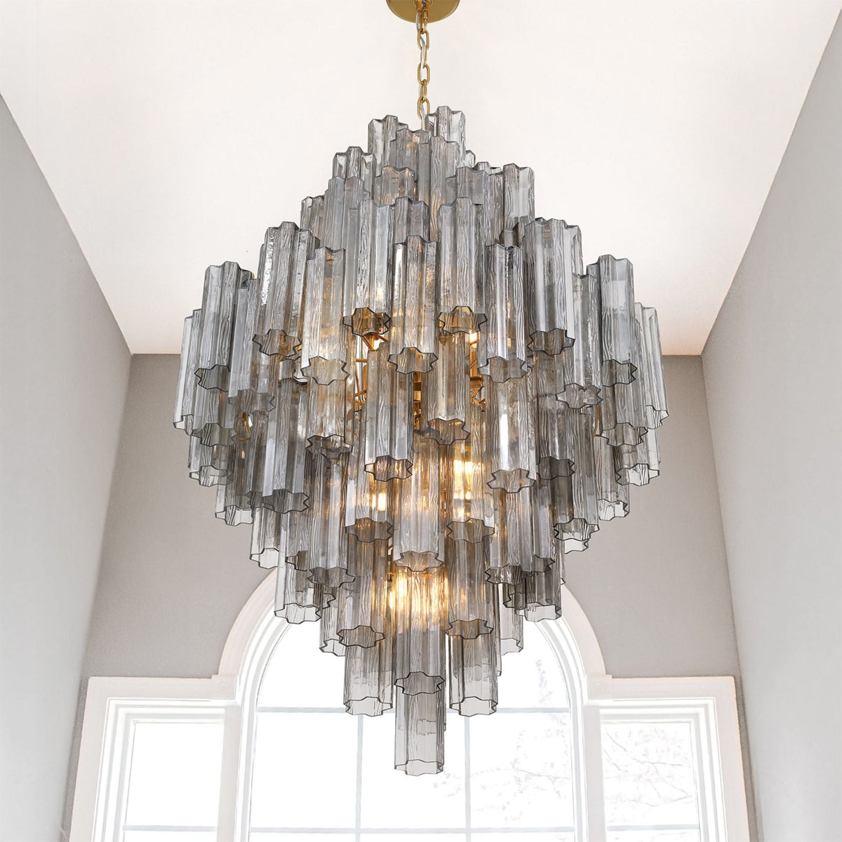 Addis Diamond Chandelier with smoke glass hanging in a corner with arched windows