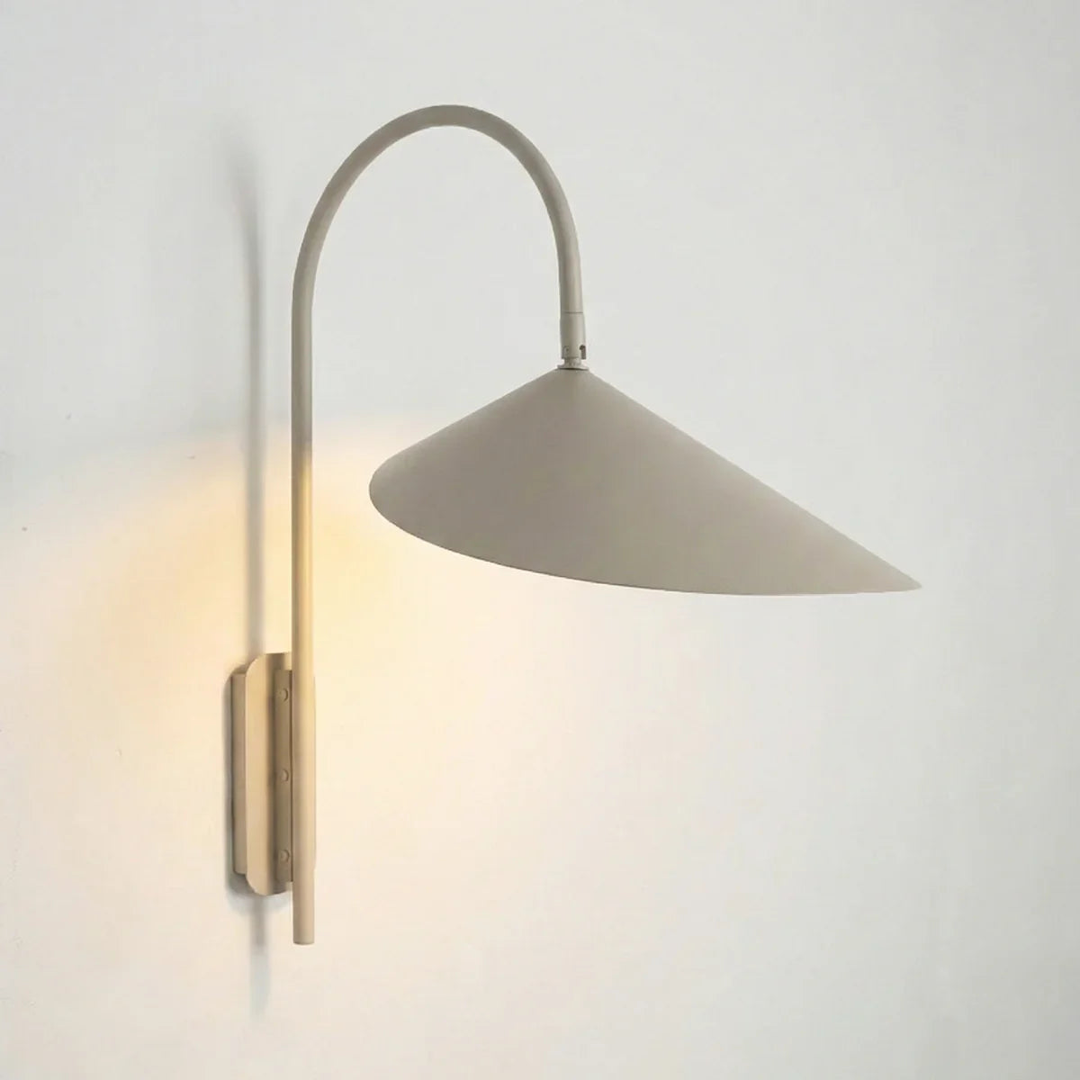 Arum Swivel Wall Lamp in brushed brass finish mounted on a plain white wall