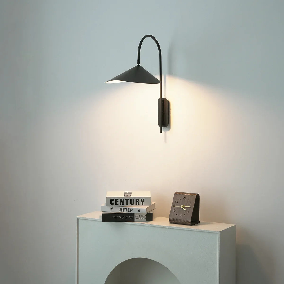 Front view of Arum Swivel Wall Lamp in matte black on a plain white wall with soft light