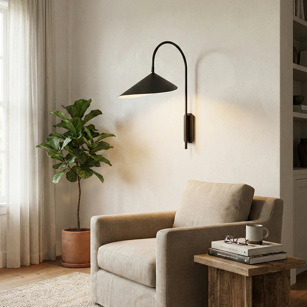 Arum Swivel Wall Lamp in matte black mounted beside an armchair in a living room