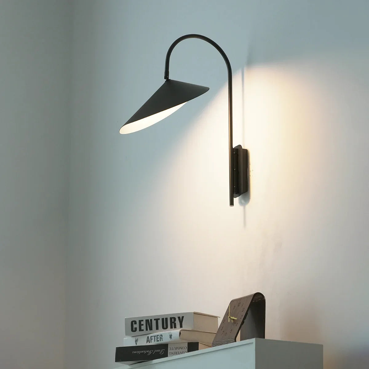 Side view of Arum Swivel Wall Lamp in matte black on a plain white wall, showing the swivel arm