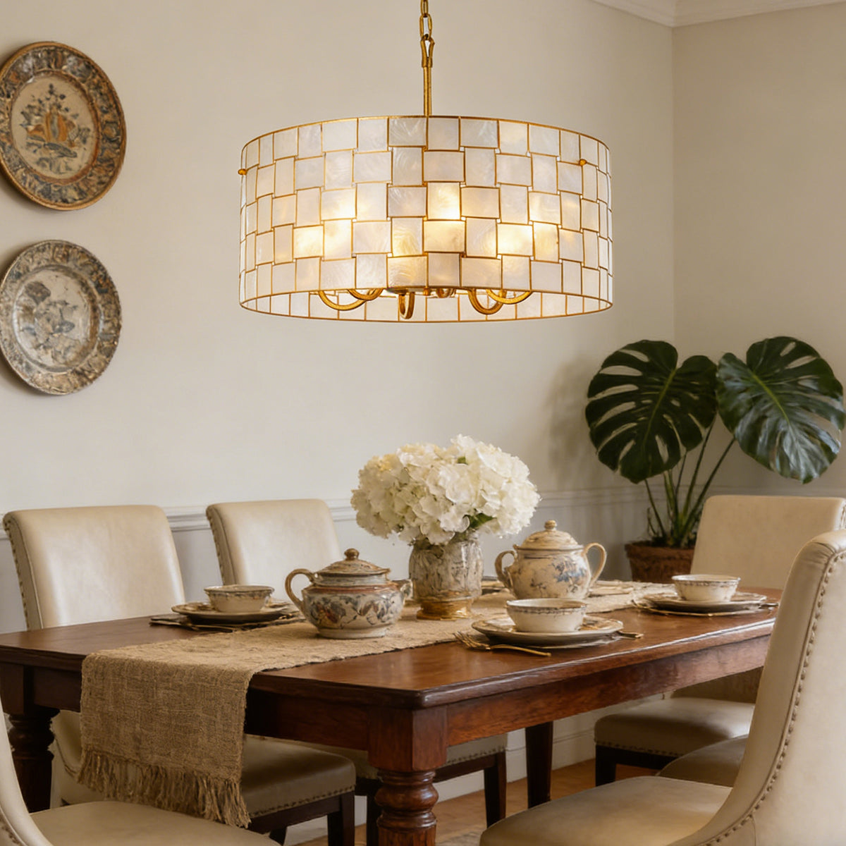 Capiz Shell Drum Chandelier above a rustic wooden dining table with ceramic decor Metavaya