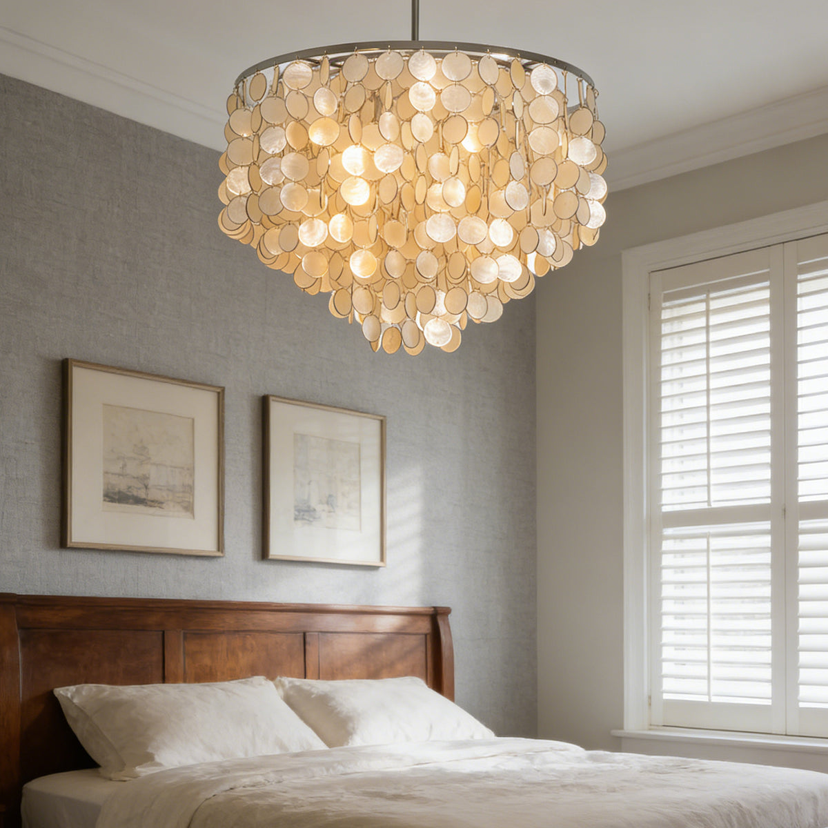 Capiz shell round chandelier hanging above a bed in a cozy neutral-toned bedroom.