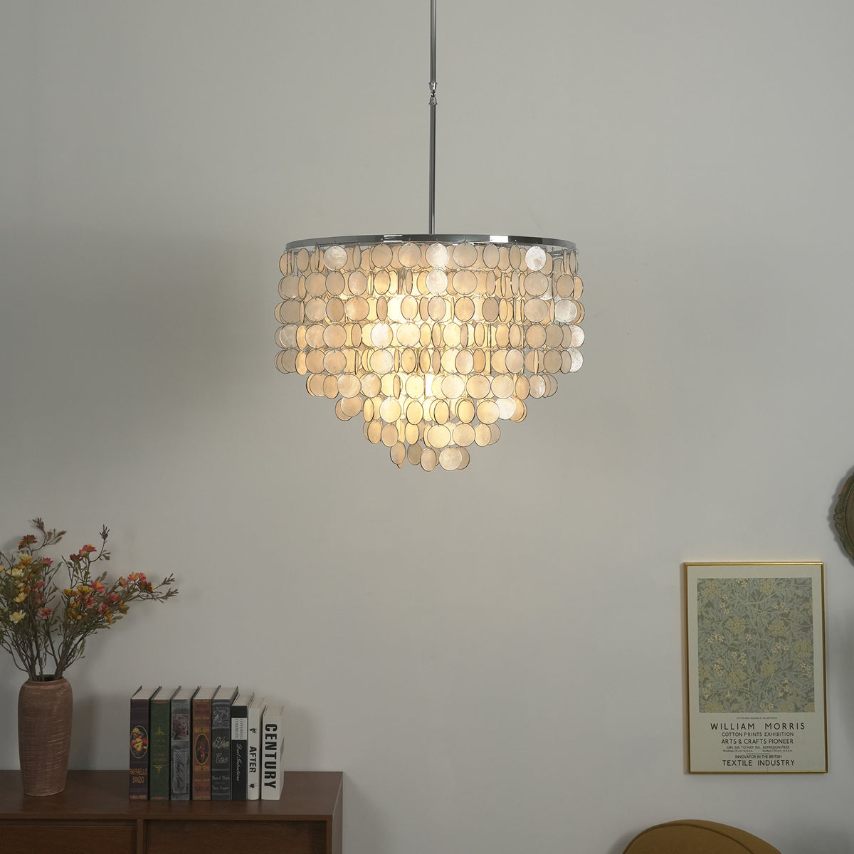 Lit capiz shell round chandelier casting a warm soft glow against a light background.