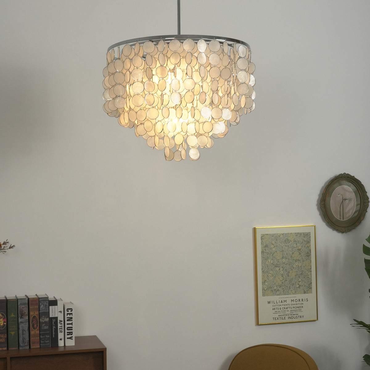 Lit capiz shell round chandelier casting a warm soft glow against a light background.