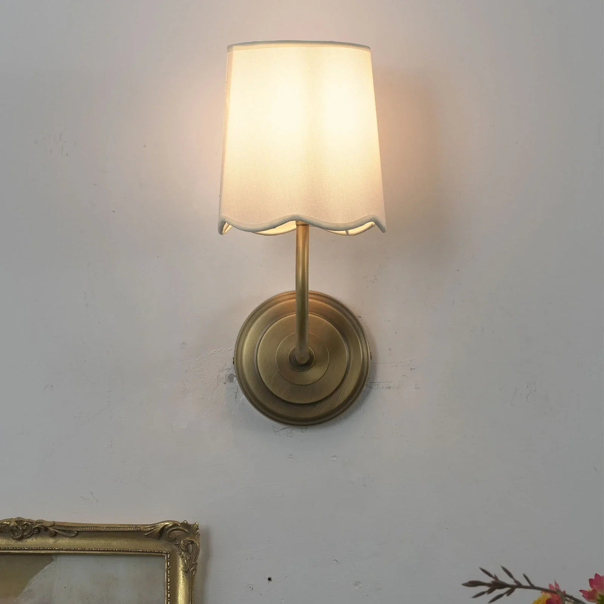 Lit Curved Arm Fabric Wall Sconce showing warm light angle projection on white wall
