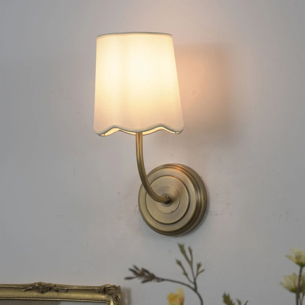 Lit Curved Arm Fabric Wall Sconce in a corner view with soft warm light