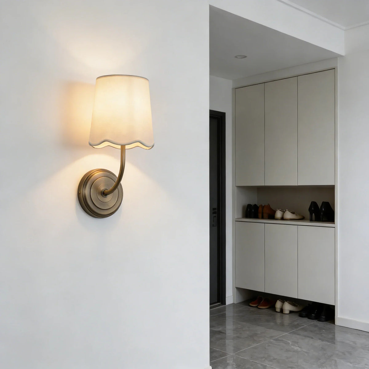 Lit Curved Arm Fabric Wall Sconce in a bright entryway with white cabinetry