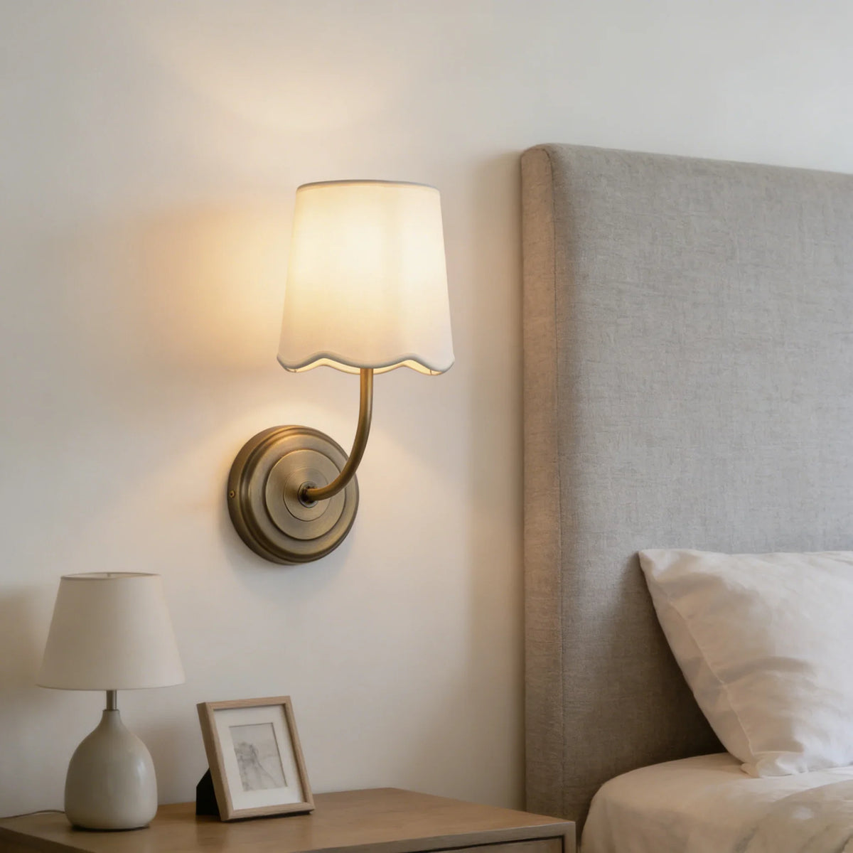 Lit Curved Arm Fabric Wall Sconce in a modern minimalist bedroom with neutral decor
