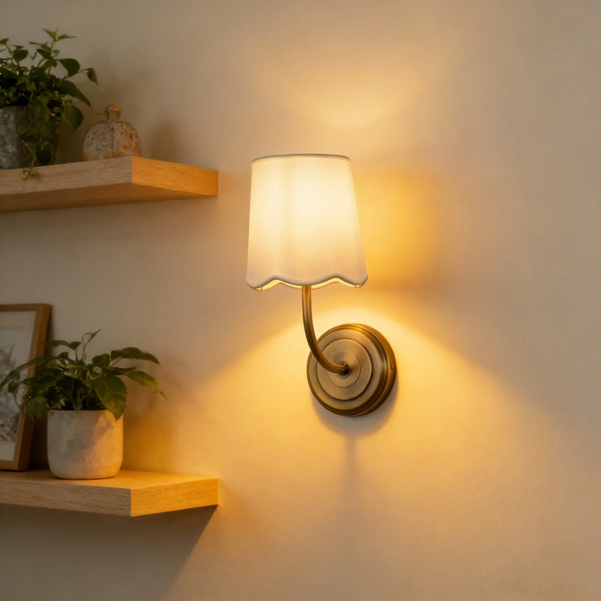 Lit Curved Arm Fabric Wall Sconce above a wooden shelf with potted plants