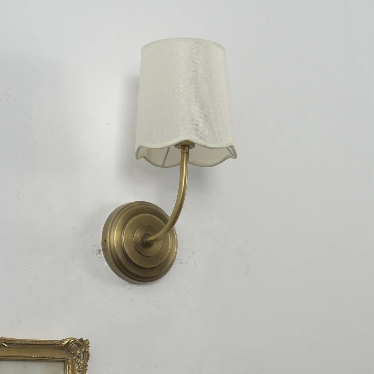 Unlit Curved Arm Fabric Wall Sconce with cream shade on a plain white wall