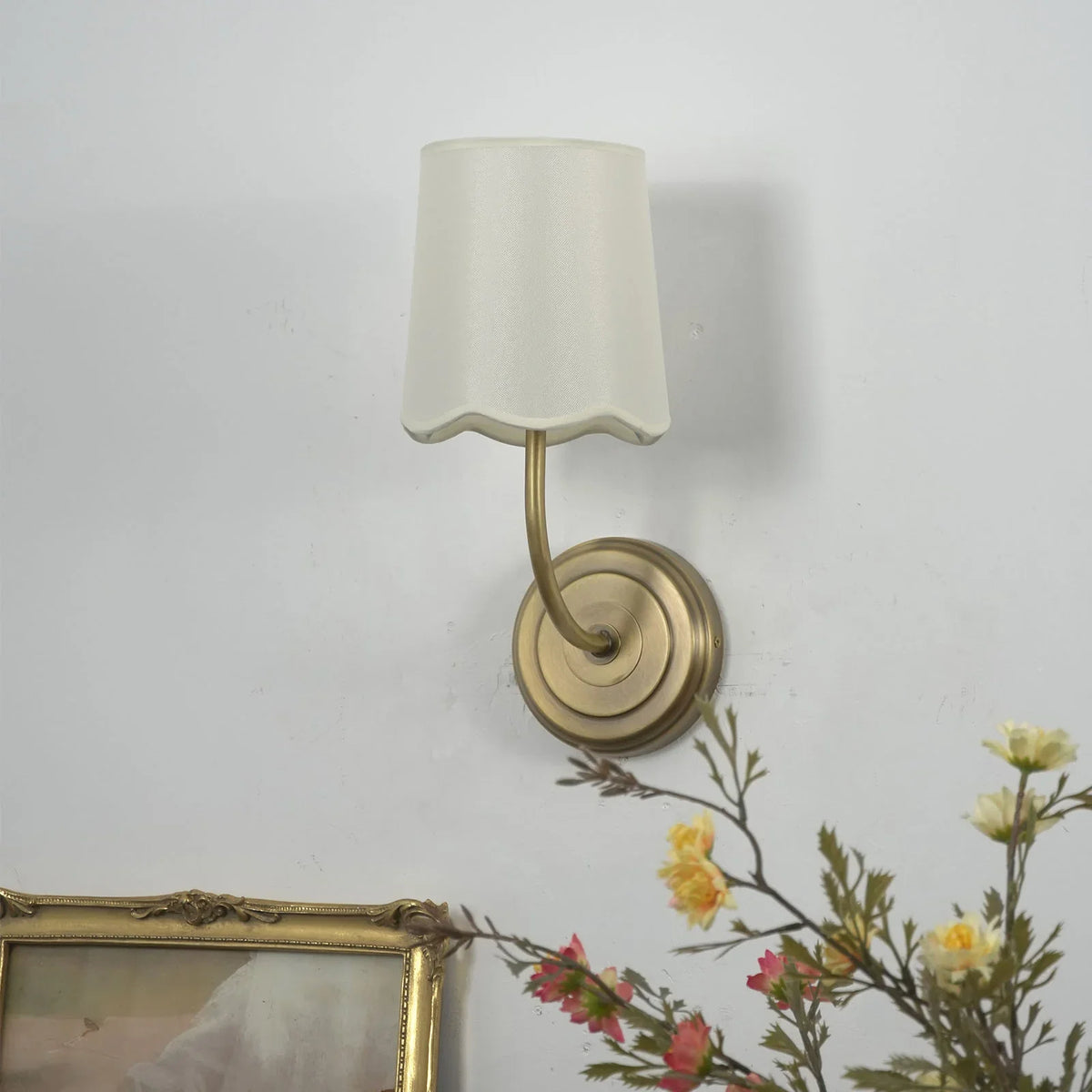 Unlit Curved Arm Fabric Wall Sconce with cream shade on a plain white wall