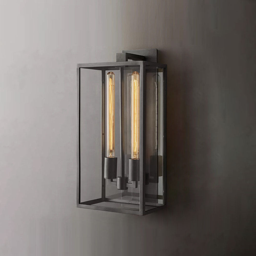 Lit black Faraday outdoor wall sconce, casting warm light through the glass enclosure.