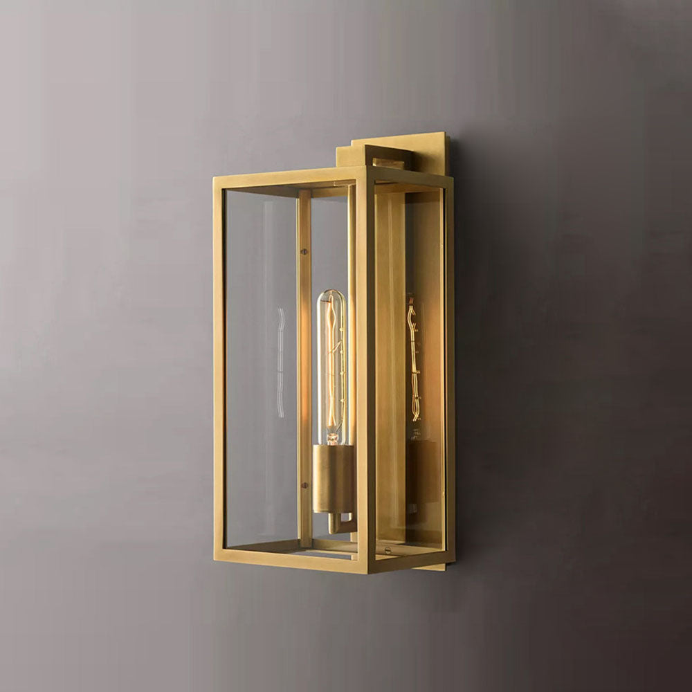 Black Faraday wall sconce mounted on a plain white wall with tropical plants nearby.