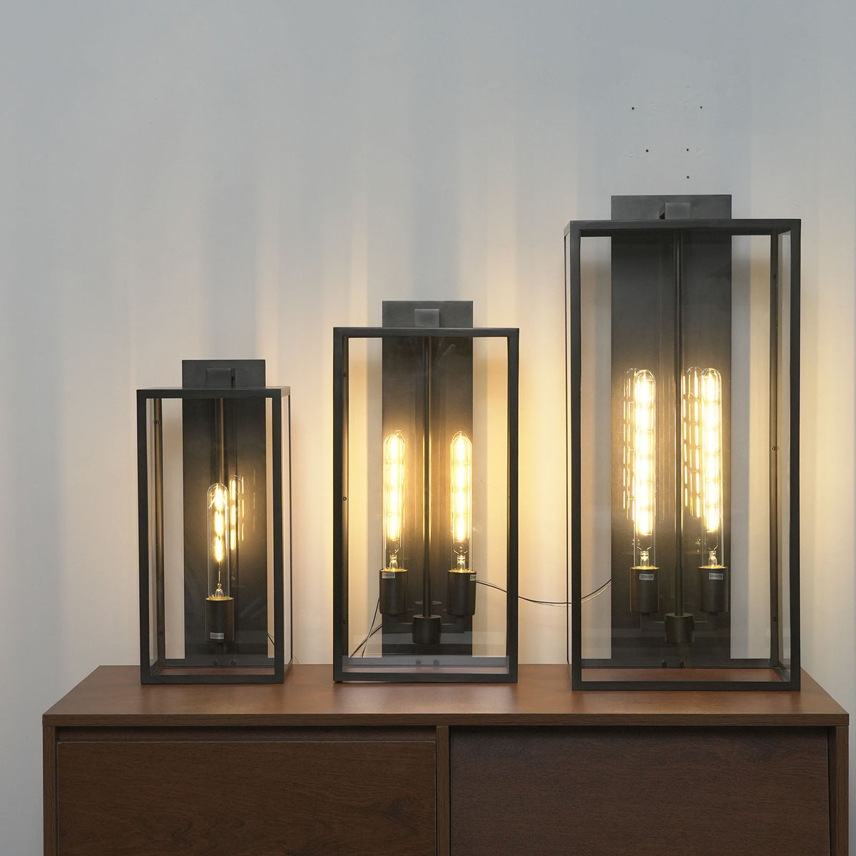Faraday outdoor wall sconces in different sizes displayed on a wooden table.