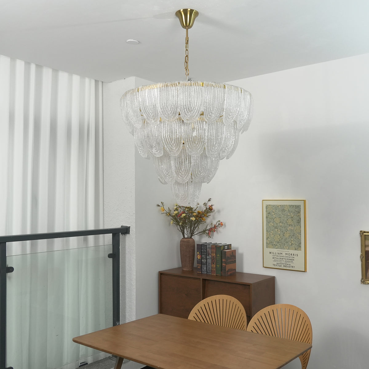 Layered glass petal chandelier above a small wooden dining table with rattan chairs.