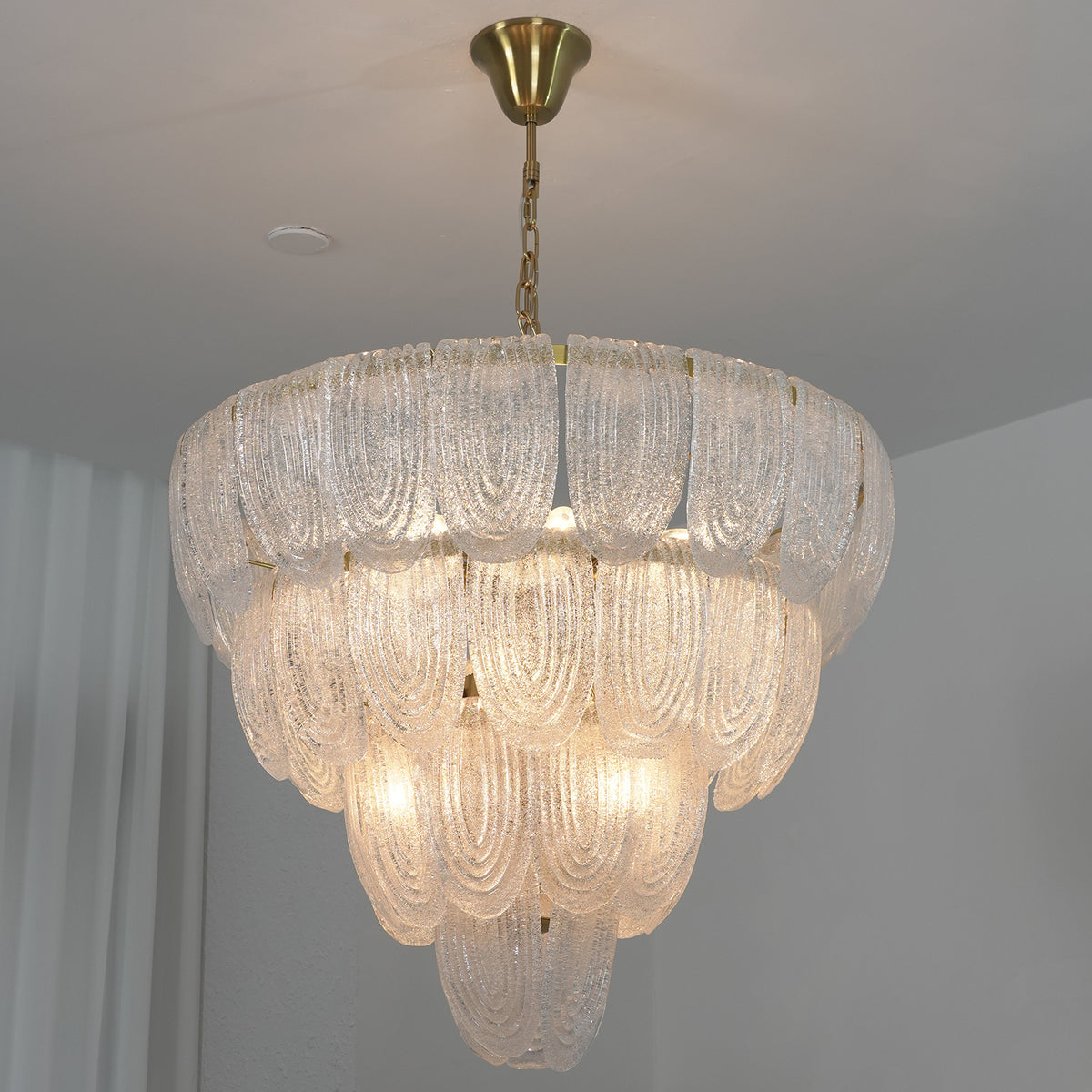 Close-up of a lit layered glass petal chandelier, showing the texture and translucency of the glass petals.