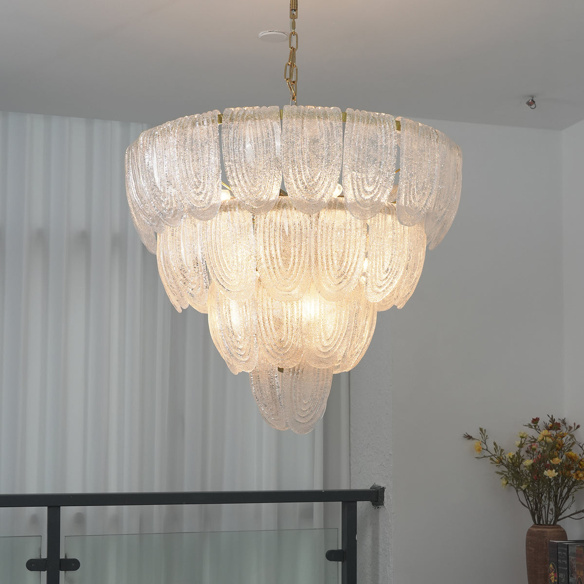 Low-angle view of a lit layered glass petal chandelier, highlighting its cascading glass layers.