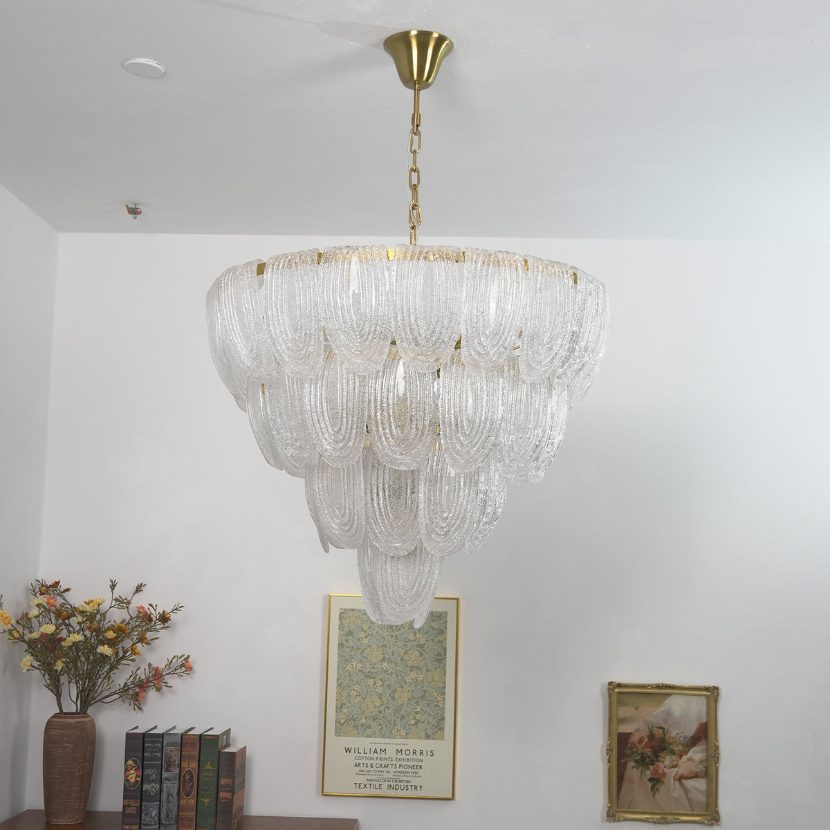 Layered glass petal chandelier in a bright living room with light walls and framed artwork.