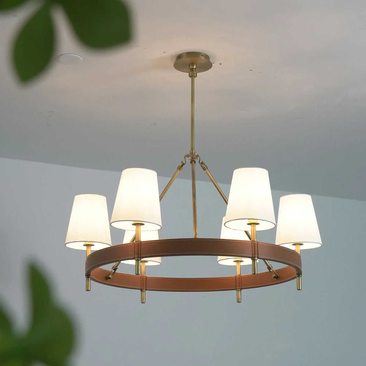 Angled view of the round Leather Halo Ring Chandelier with warm light projection