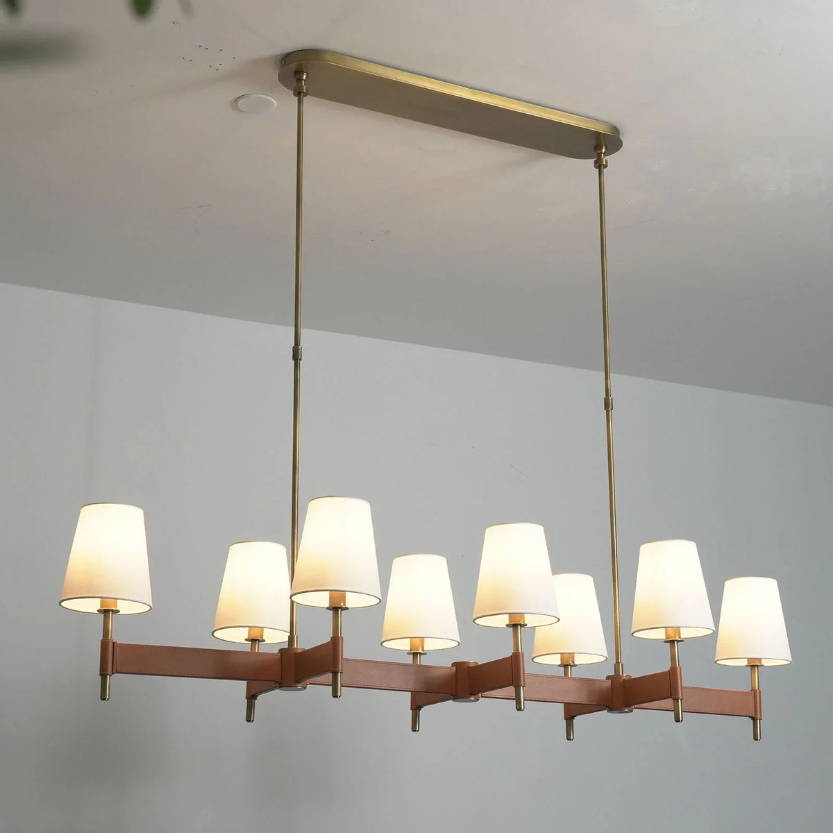 Linear pendant version of the Leather Halo Ring Chandelier above a dining table