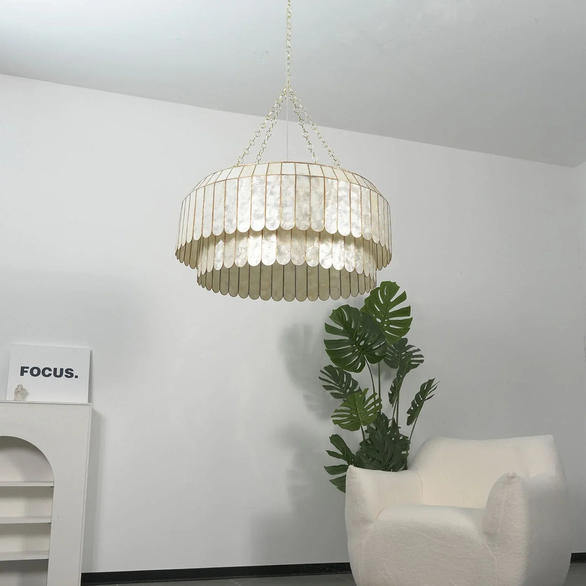 Silver-toned Light Luxury Shell Chandelier front view in a white room with plants