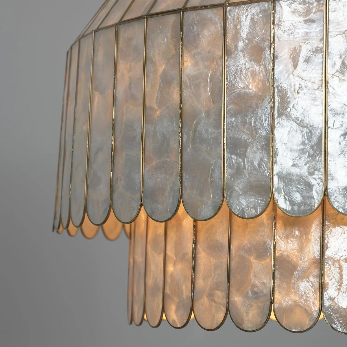 Close-up of glowing silver-toned capiz shells on the chandelier with warm light