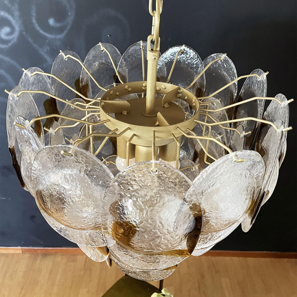 Mazzega-style glass chandelier hanging in a room with framed artwork and classic furniture.