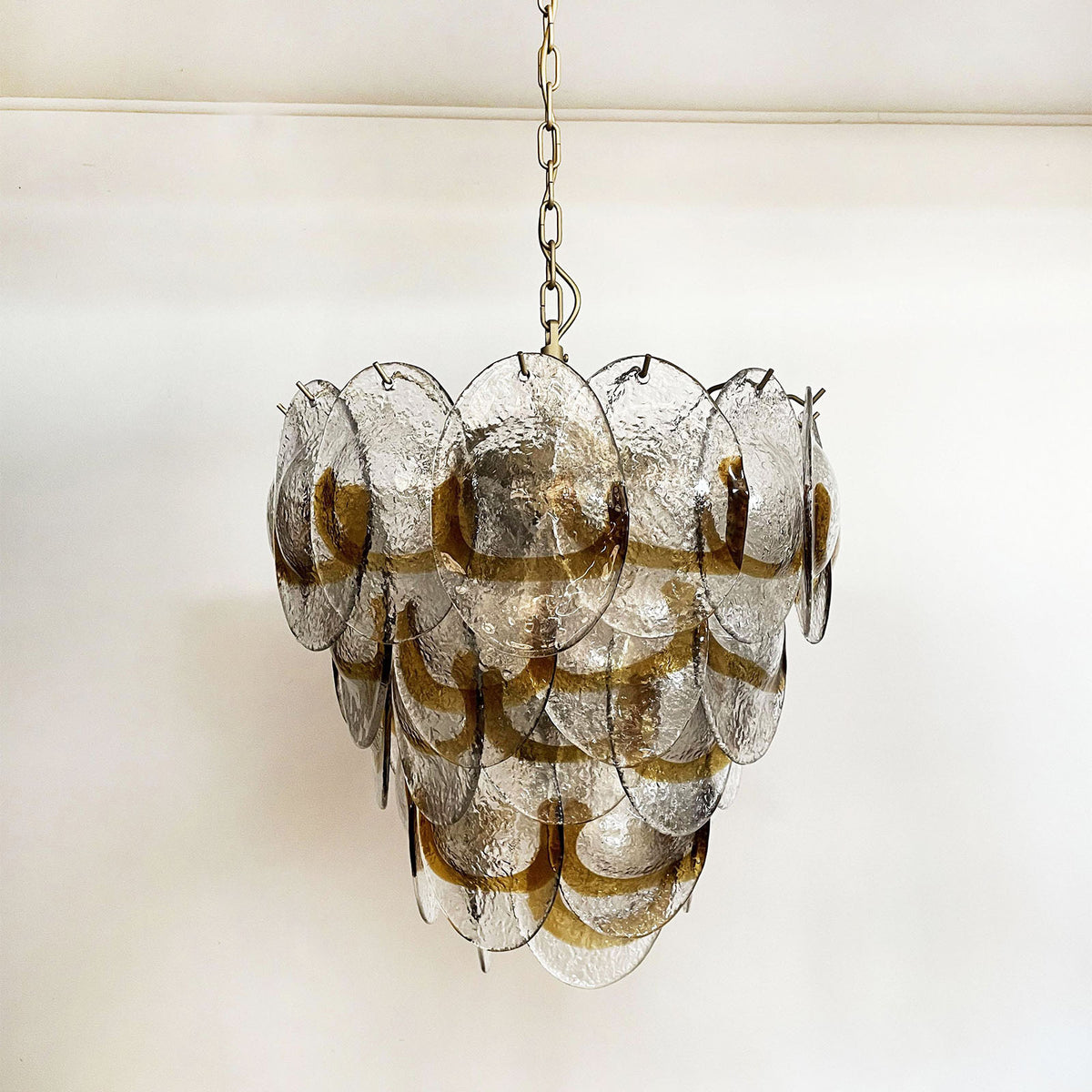 Mazzega-style glass chandelier hanging in a corner with dark and light walls, next to a framed artwork.