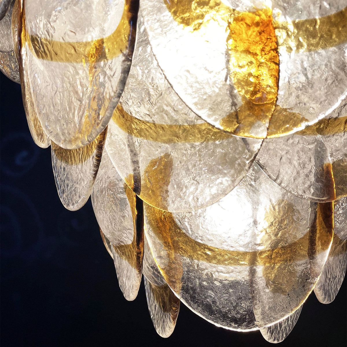 Close-up of a single glass disc on the Mazzega-style chandelier, showing its frosted texture and amber stripe.
