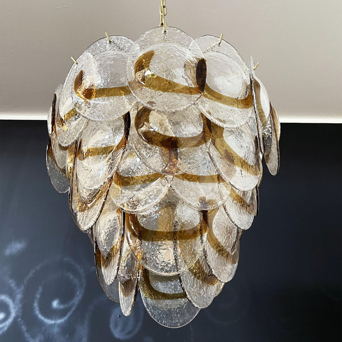 Lit Mazzega-style glass chandelier, showing warm light filtering through the textured glass discs.
