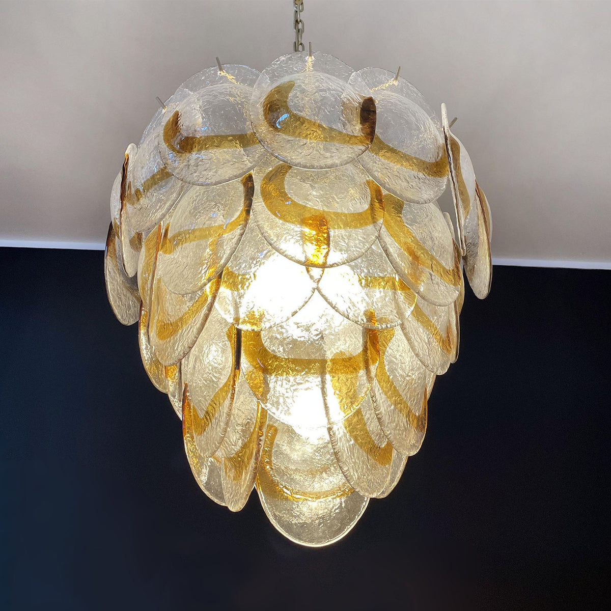 chandelier-low-angle-room-metavaya Low-angle view of the Mazzega-style glass chandelier hanging in a room with classic metal chairs.
