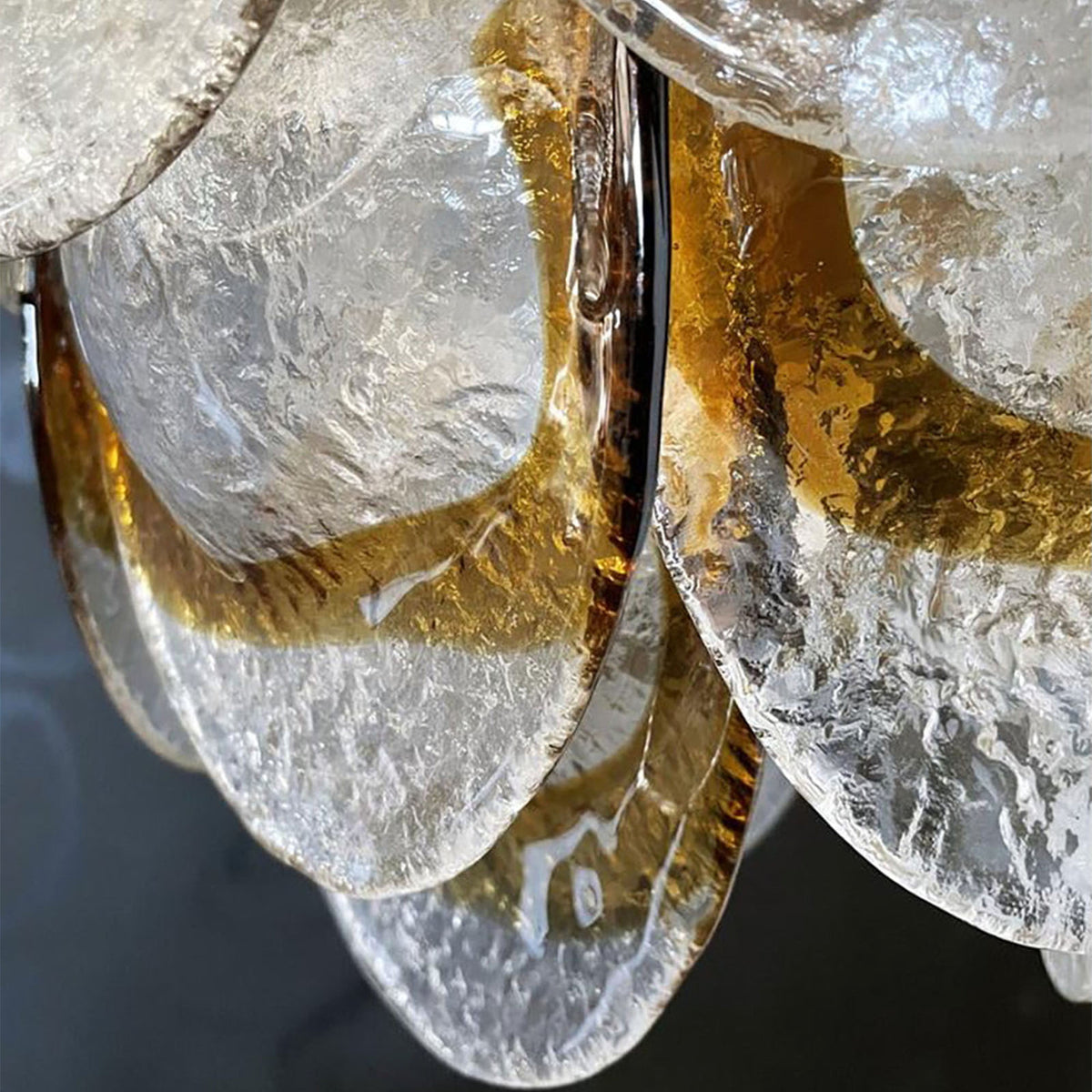 Mazzega-style glass chandelier hanging against a plain white wall, with polished gold hardware.