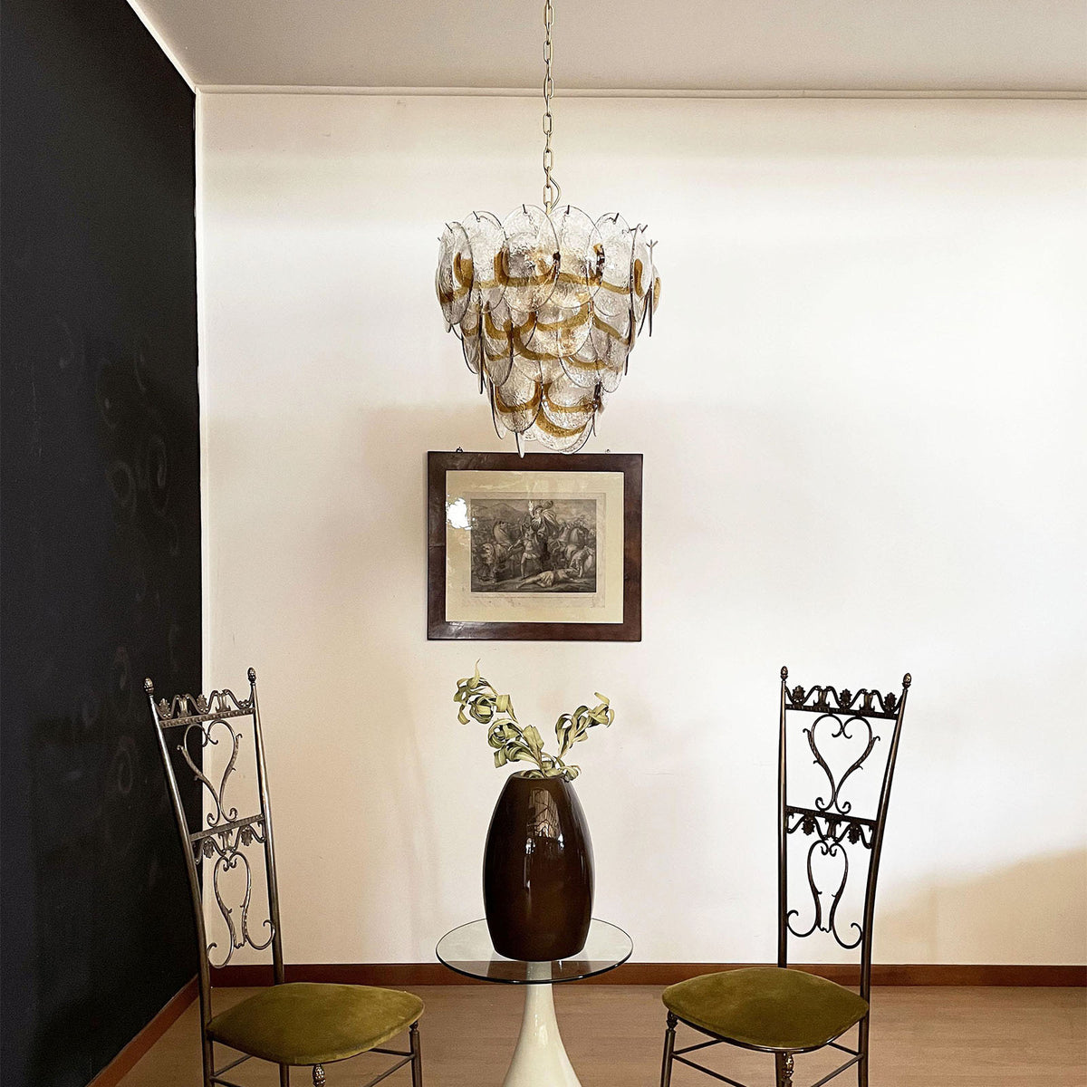 Mazzega-style glass chandelier hanging in a corner with black and white walls.