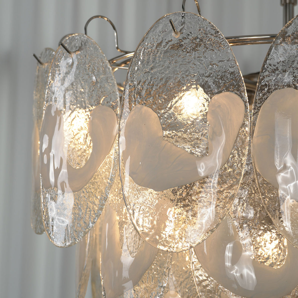 Mazzega-style white glass chandelier with polished nickel hardware, lit and hanging against a light wall.