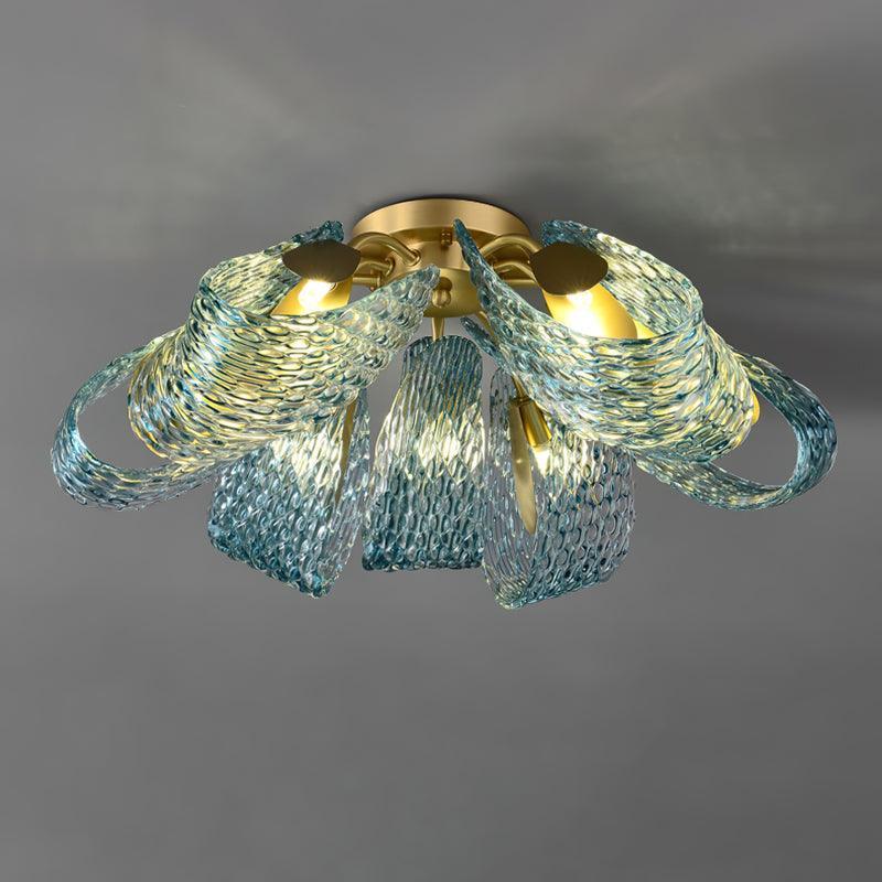 Close-up of the lit blue glass petals, showing warm light diffusing through the textured translucent glass.