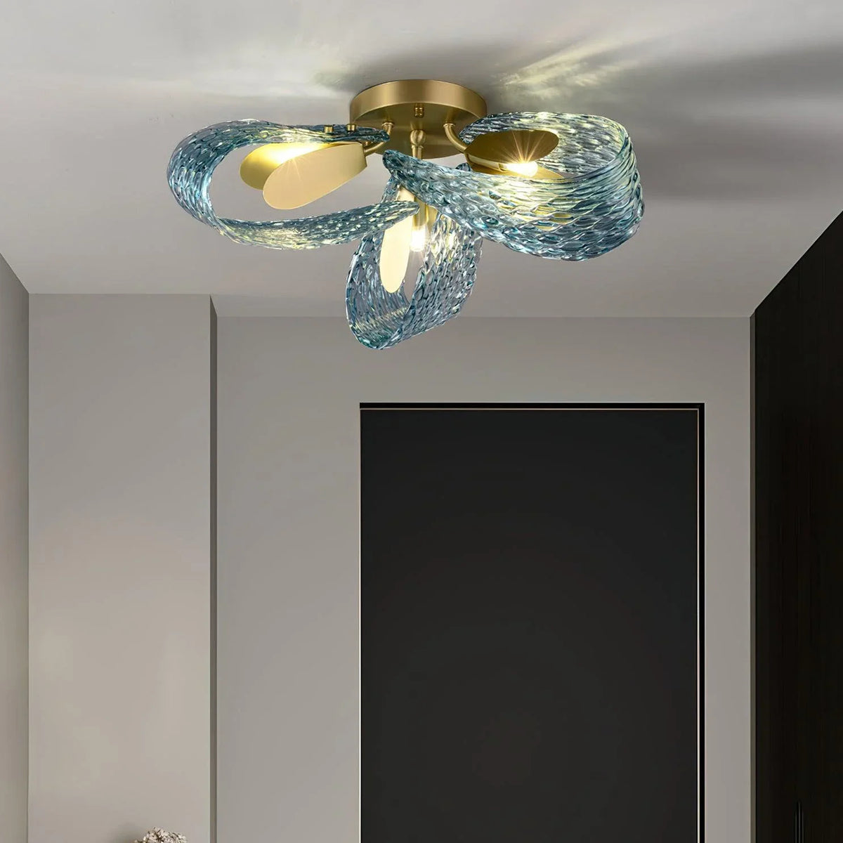 Petal blue glass ceiling light installed in a bright hallway with light-colored walls.