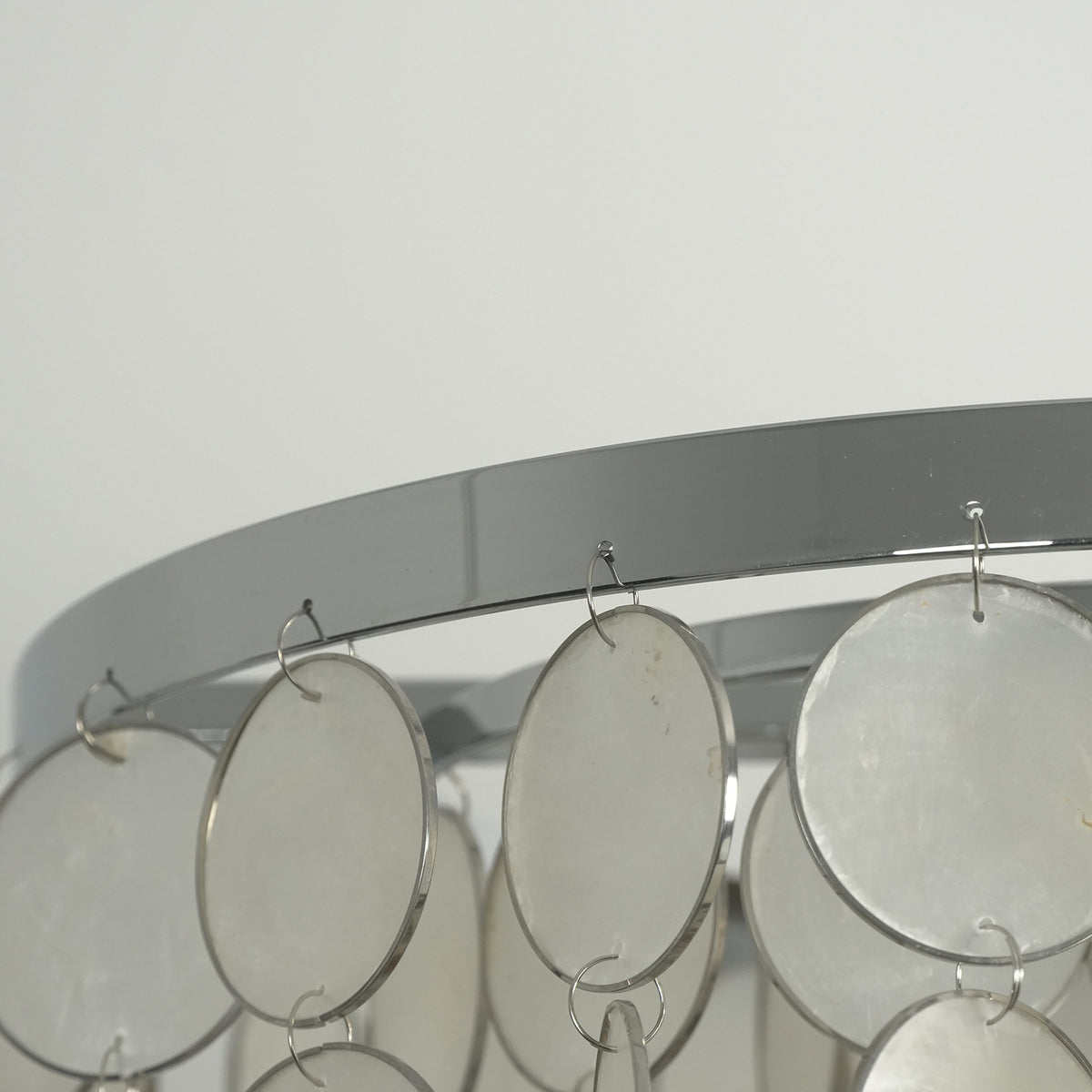 Close-up of the natural texture and iridescent finish of individual capiz shell discs on the chandelier.