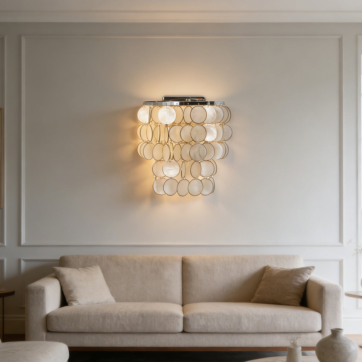 Pair of round tiered capiz shell wall sconces mounted above a marble dining table in a bright dining room.