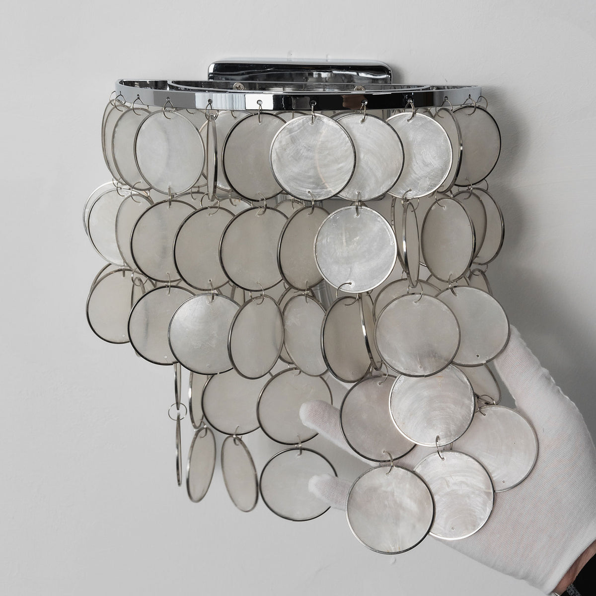 Front view of the round tiered capiz shell wall sconce on a plain white background.