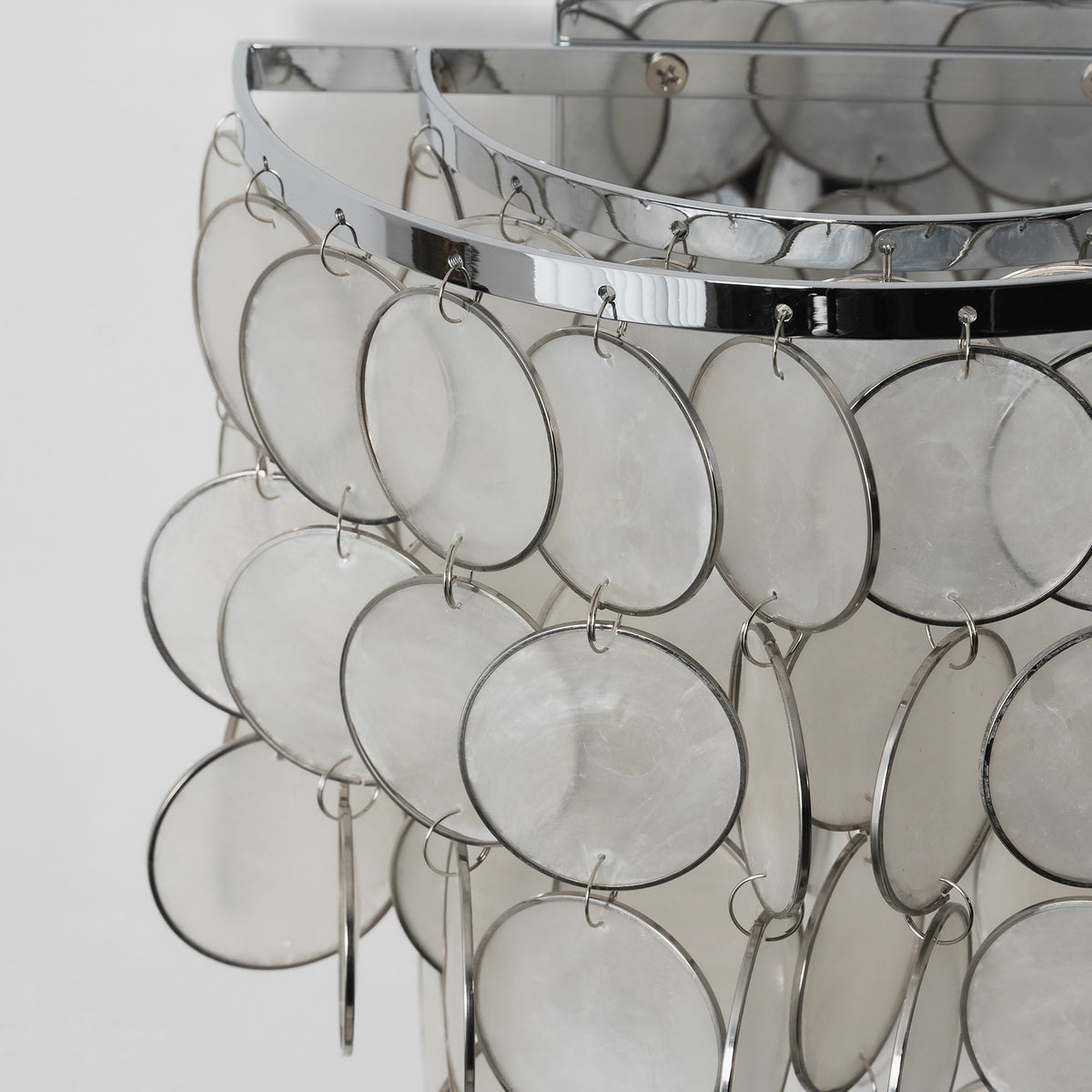 Close-up of the natural texture and iridescent finish of capiz shell discs on the wall sconce.