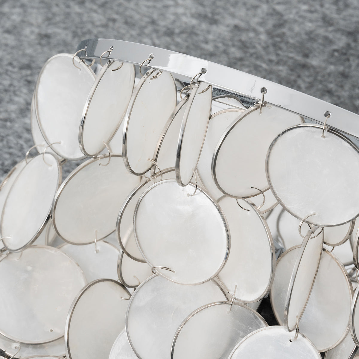 Close-up of overlapping capiz shell discs on the tiered wall sconce, showing their layered arrangement.