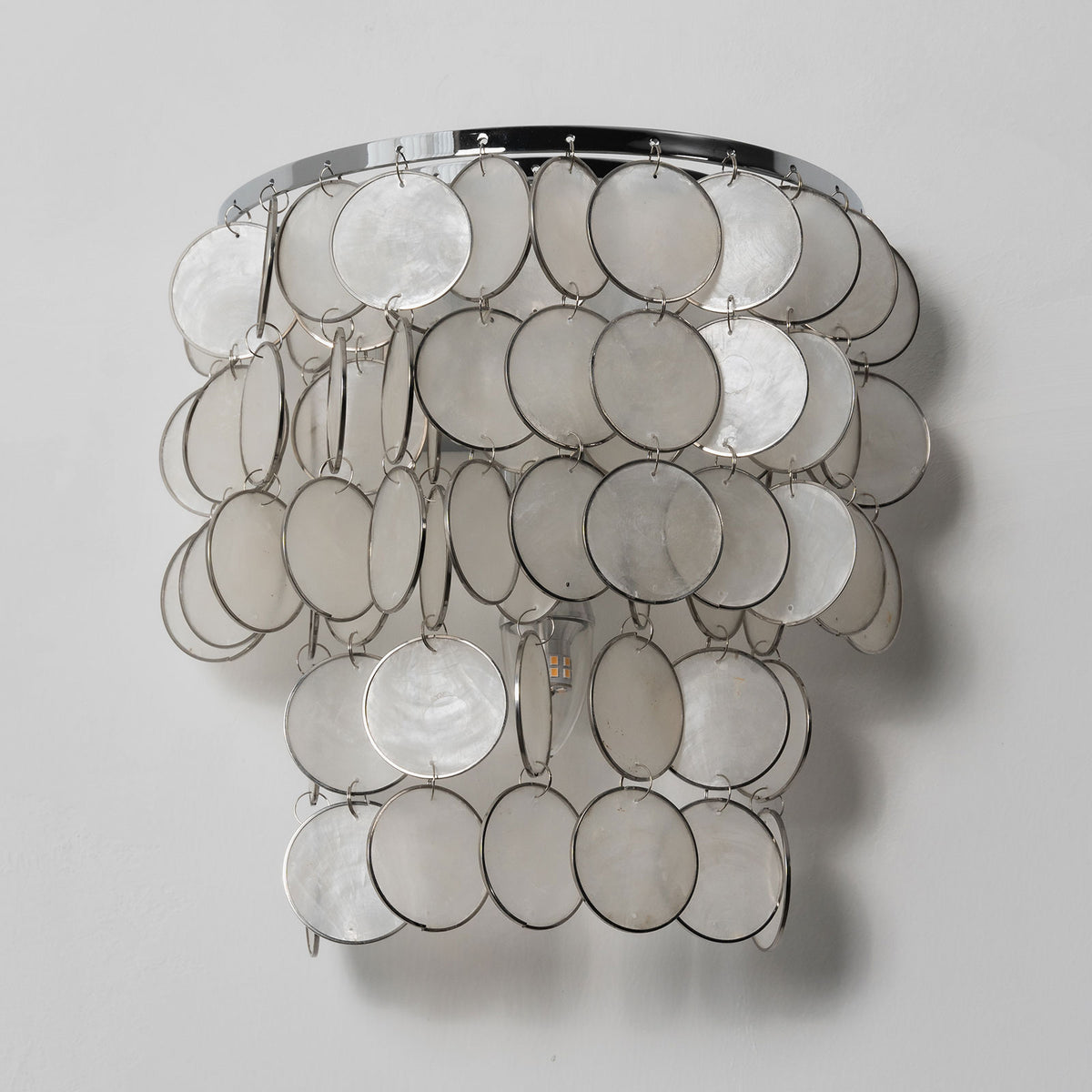 Side view of the round tiered capiz shell wall sconce, isolated on a white background.