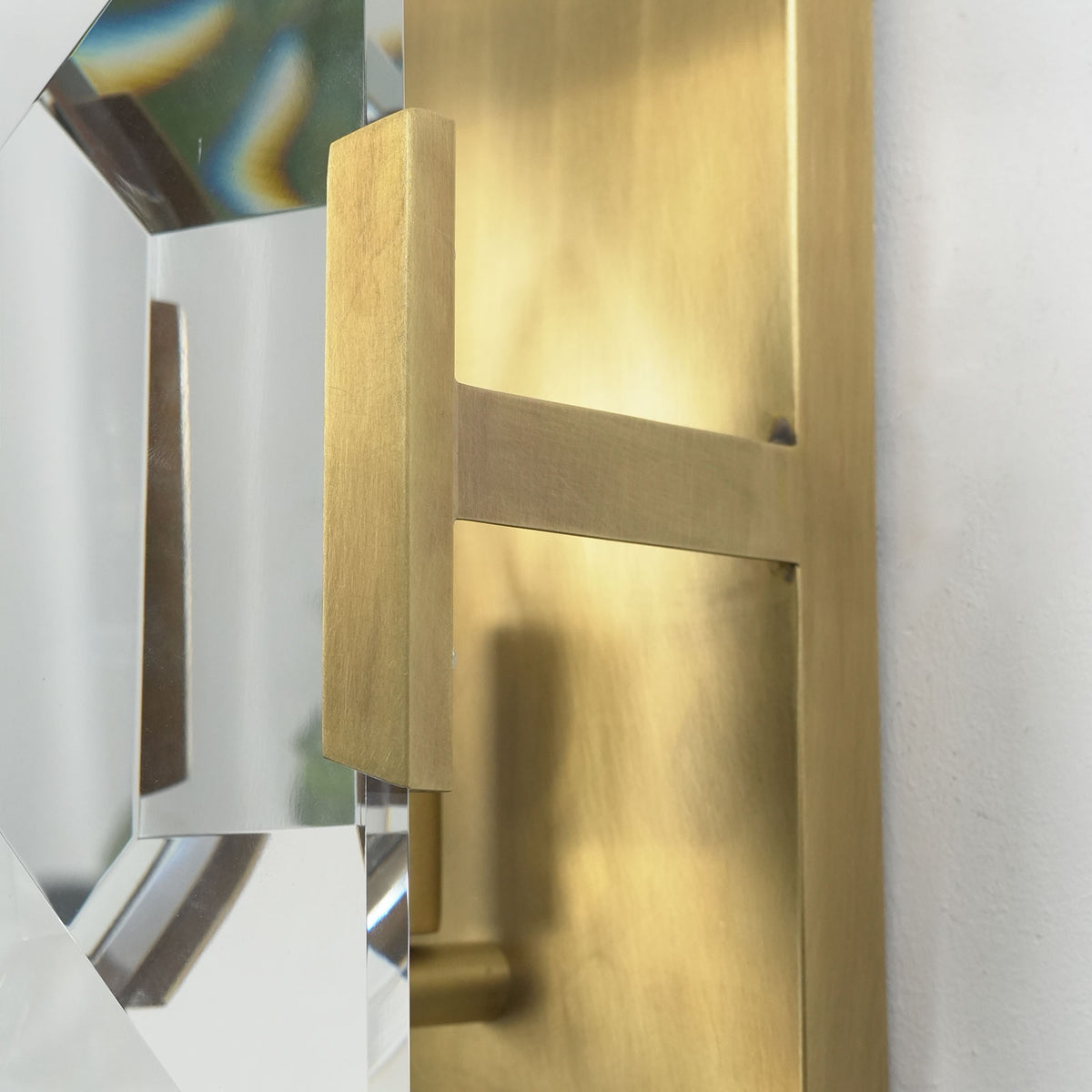 Lit single-headed crystal wall lamp, showing warm light filtering through faceted crystal panels.