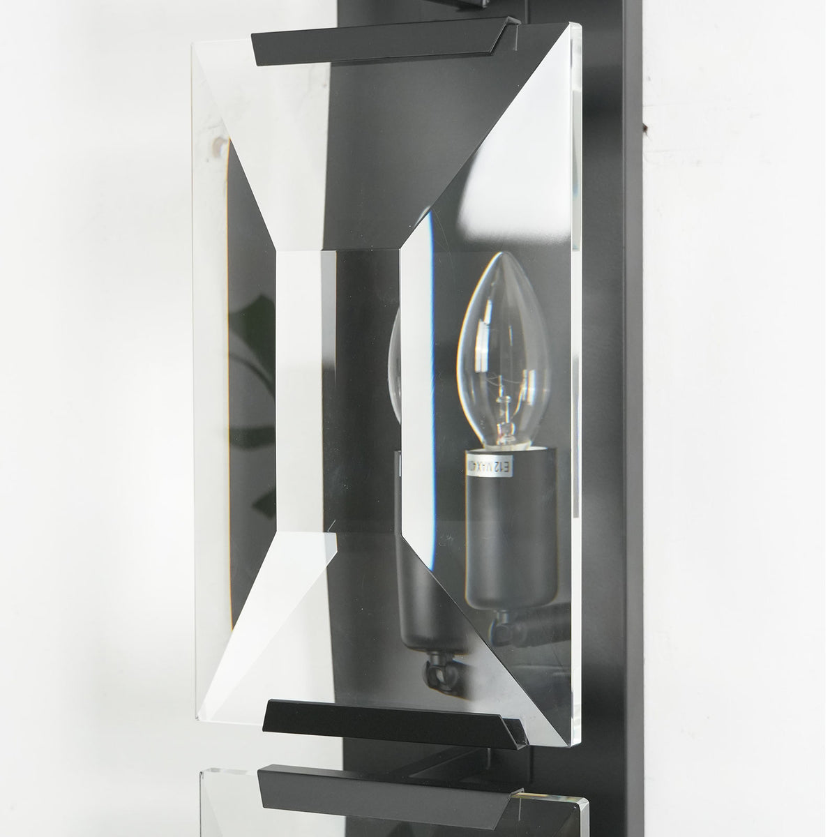 Side view of a lit single-headed crystal wall lamp, highlighting its crystal facets and brass frame.