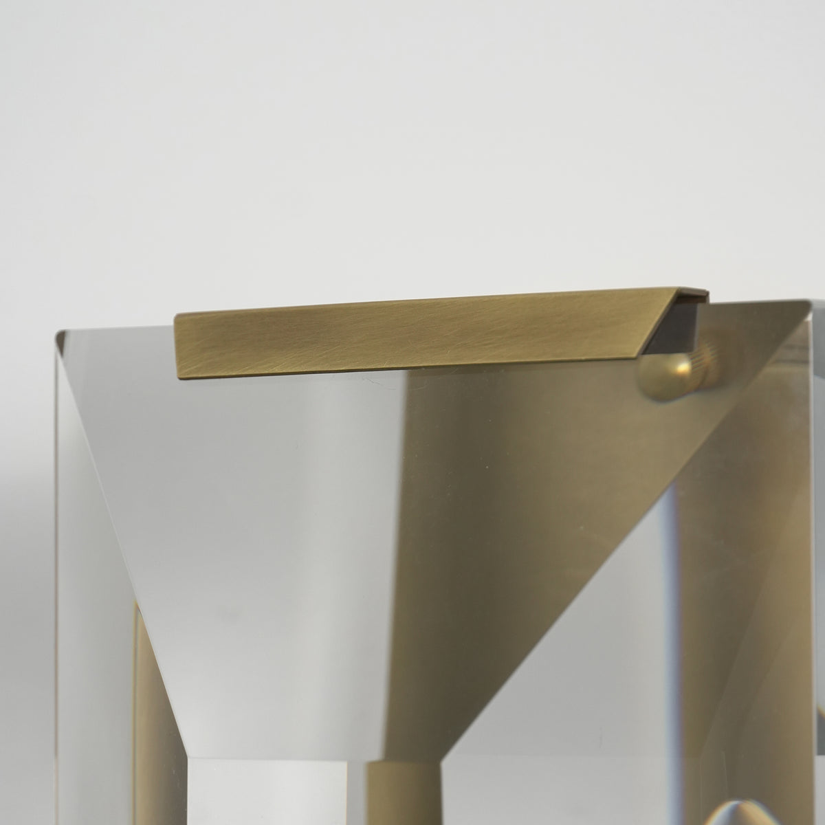 Close-up of the brushed brass frame on the three-headed crystal wall lamp.
