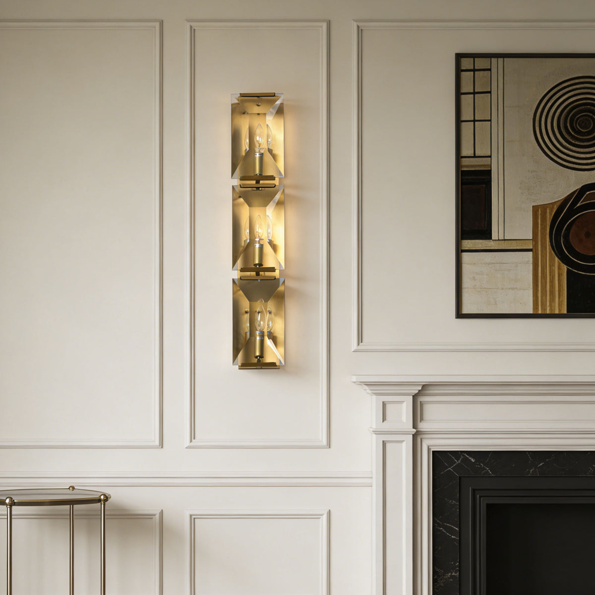 Three-headed crystal wall lamp mounted on a paneled wall above a classic fireplace.