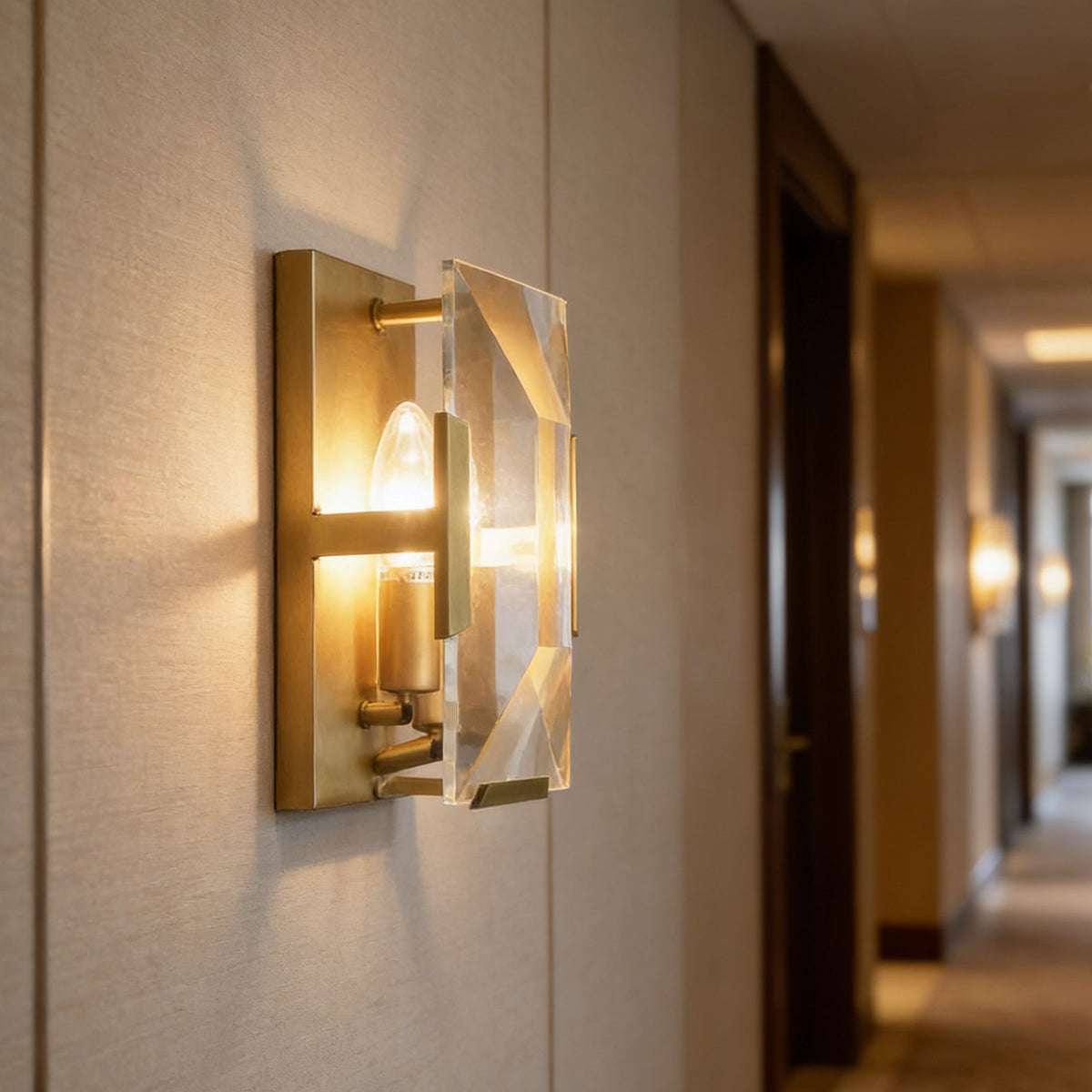 Three-headed crystal wall lamp mounted on a wall in a bright hallway.