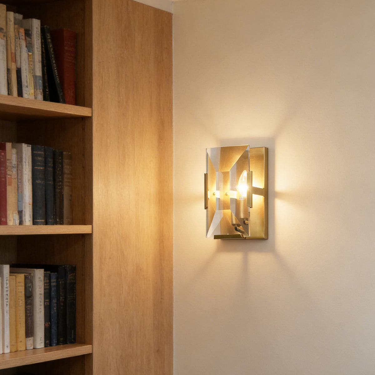 Three-headed crystal wall lamp mounted beside a wooden bookshelf in a modern home office.